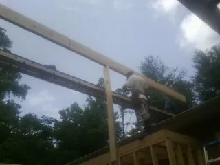 Carpenter setting a ridge beam over a new addition frame — Ice Dam Removal by Roofing Brothers in Bassfield