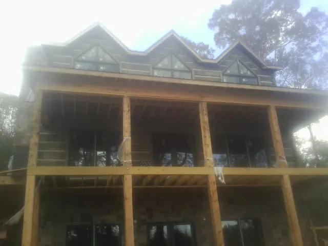 Dormers and porch framing on a large log home under construction — Roof Coating work by our crew in Bassfield