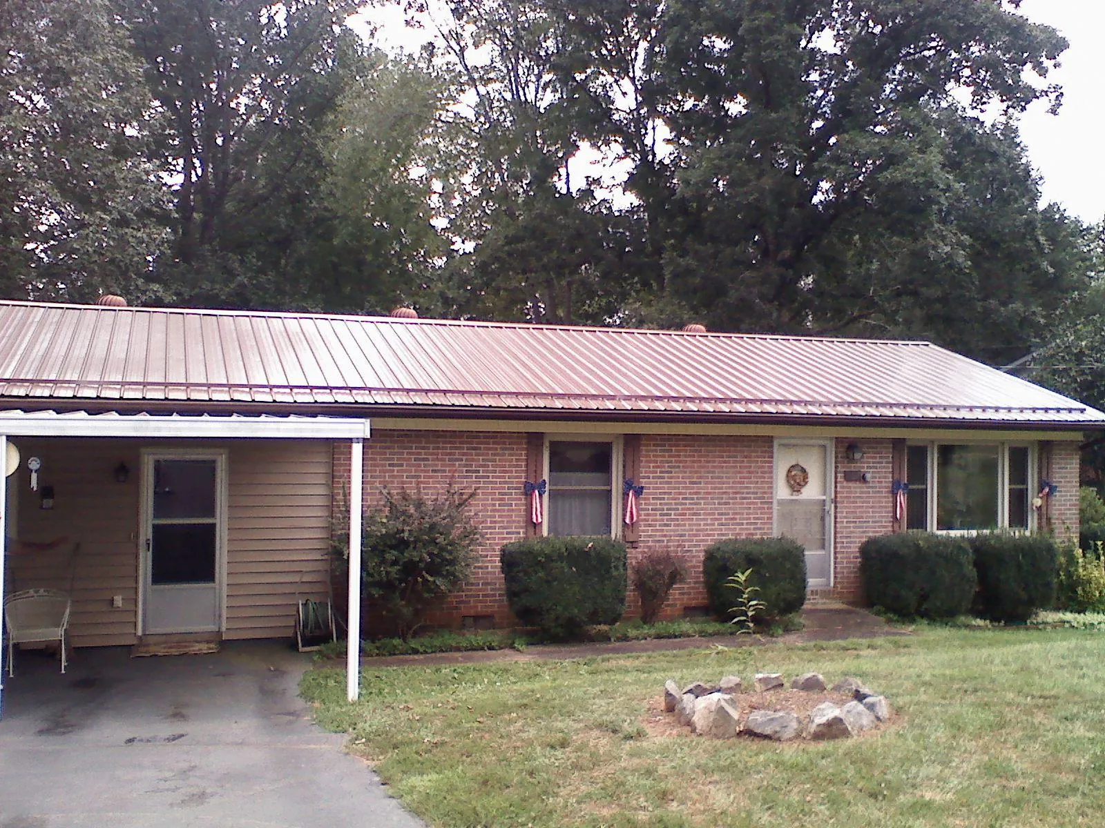 Bronze metal roof and carport on a brick ranch home — Roof Repair work by our crew in Bassfield