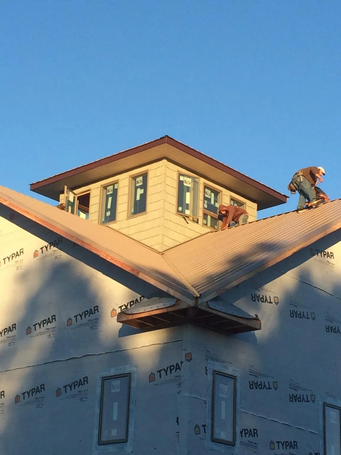 Roofers working around a rooftop cupola on a new metal roof at sunset — Roof Waterproofing in Bassfield by Roofing Brothers